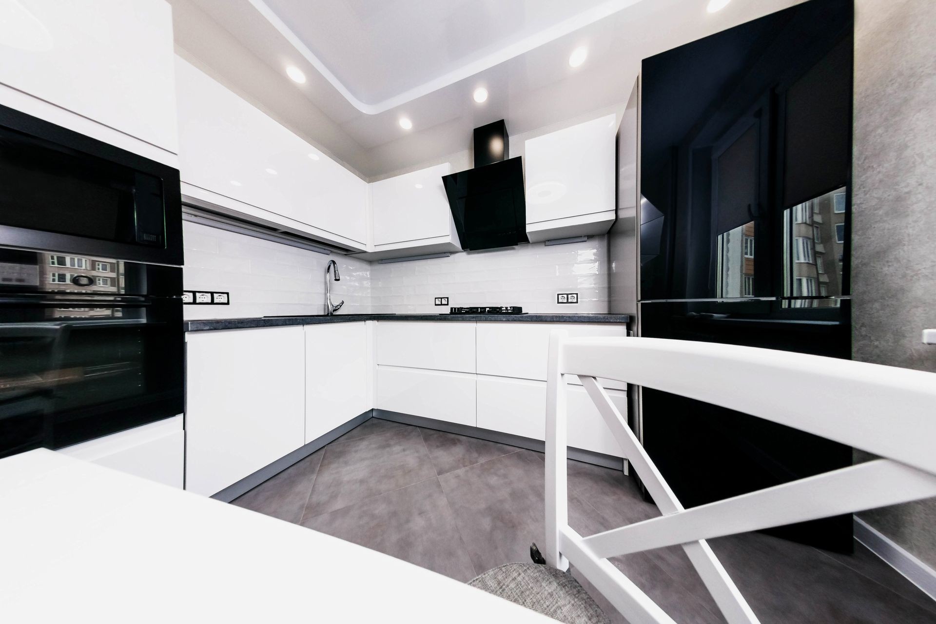 interior of new modern technological white kitchen. black refrigerator.